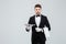 Attractive butler in tuxedo standing and holding silver empty tray