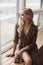 Attractive calm lady in leopard dress sitting on windowsill