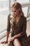 Attractive calm lady in leopard dress sitting on windowsill