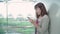 Attractive casual happy young Asian woman in international airport, using and checking her smartphone standing in terminal hall.