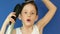 Attractive caucasian boy 7 years old with a hair dryer and a comb in the bathroom creates a hairstyle for himself.Cheerful little