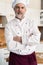 Attractive Caucasian chef standing with arms crossed in a restaurant kitchen