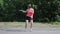 Attractive caucasian girl in pink shirt with headphones dancing in park. Young woman doing funny and ridiculous moves. Girl smilin