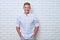 Attractive Caucasian man leaning on a white brick wall and holding his hands in pockets