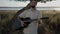 Attractive caucasian man playing acoustic guitar while standing on the roadside of country Spain backlit with sunset