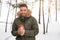 Attractive Caucasian man stands in winter forest near his car