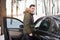 Attractive Caucasian man stands in winter forest near his car