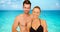 Attractive Caucasian millennial couple standing at the beach smiling at camera