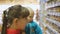 Attractive caucasian woman choosing infant food in supermarket holding her baby in arms. Close-up shot of mom and baby