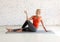 Attractive caucasian woman practice hatha yoga indoor in loft white studio. Seated side twist pose, selective focus.