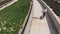 Attractive caucasian woman is walking with a scooter in a beautiful modern city on a sunny day, aerial view. Modern eco