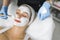 Attractive caucasian woman with white cosmetic band on her hair during facial treatment. Professional aesthetician