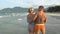 Attractive cheerful couple walking at beach. Hug each other and kiss