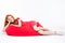 Attractive cheerful woman lying on red bean bag