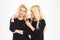 Attractive cheerful young blonde sisters twins talking and looking away