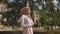 Attractive confident muslim woman in hijab walking in park and looking around during sunny day, tree in background