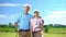 Attractive couple of golfers with clubs posing on camera at course, sport school