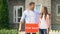 Attractive couple hugging installing for sale signboard in front of house, life