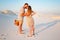 attractive couple kissing on the white sand beach or in the desert or in the sand dunes, guy and a girl with a basket in their ha