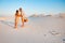 Attractive couple kissing on the white sand beach or in the desert or in the sand dunes, guy and a girl with a basket in their han