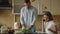 Attractive couple in the kitchen early morning. Beautiful girl chatting phone while her boyfriend cooking breakfast