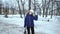 Attractive curly girl in winter. Young beautiful woman in a blue jacket and white hat on a background of white snow. The