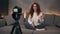 Attractive curly red headed young girl vlogger is talking in front of camera recording video for online blog in internet