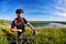 Attractive cyclist standing on the hill with mountain bicyclist against beautiful river.