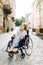 Attractive disabled blond young girl in blue dress sitting in a wheelchair, outdoors in the city