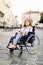 Attractive disabled young woman in blue dress sitting in a wheelchair, outdoors in the city