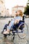 Attractive disabled young woman in blue dress sitting in a wheelchair, outdoors in the city
