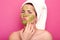 Attractive emotional young beauty has green mask on her face, day to have spa procedures, protrudes her lips, has unpleasant