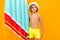 Attractive European blond boy in a summer panama and yellow swimming trunks with an inflatable swimming board on an