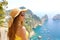 Attractive fashion woman with sunglasses and straw hat enjoying Capri sight from terrace, Capri Island, Italy