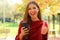 Attractive fashion woman using smart phone shows thumb up outdoor on Autumn