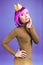 Attractive fashionable young woman in stylish luxury dress, cut pink hair on violet background. Brightful makeup with