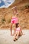 An attractive fellow stands near a beautiful girl in a pink swimsuit on a beach on a natural blurred background.