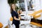 Attractive female dentist doctor standing in her office, with a female patinet in the chair