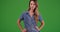 Attractive female millennial standing with hands on hips on green screen