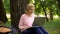 Attractive female pensioner sitting in park with laptop and surfing the net, app