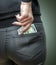 Attractive female placing wad of cash into back pocket of her jeans.