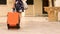 Attractive female rolling wheeled suitcase, leaving hotel, summer vacation