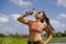 Attractive and fit Asian runner woman holding isotonic bottle drinking water after training and running series workout at outdoors