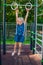 Attractive fit young woman in military colored sport wear girl pulls up on the rings at street workout area. The healthy lifestyle