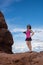 Attractive fit young woman photographer stands on top of a red rock formation in Arches National Pa