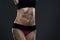 Attractive fitness woman on gray background in studio. Muscular abdomen close-up