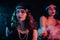Attractive flappers women dressed in style of Roaring twenties posing on neon smoky background. Vintage, retro party