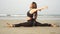 Attractive flexible woman sits on a twine on the sea beach