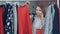 Attractive girl choosing clothes in modern shop and talking on mobile phone. Close-up shot of colourful skirts and