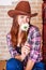 Attractive girl in a cowboy hat with straight long hair holds a chamomile flower